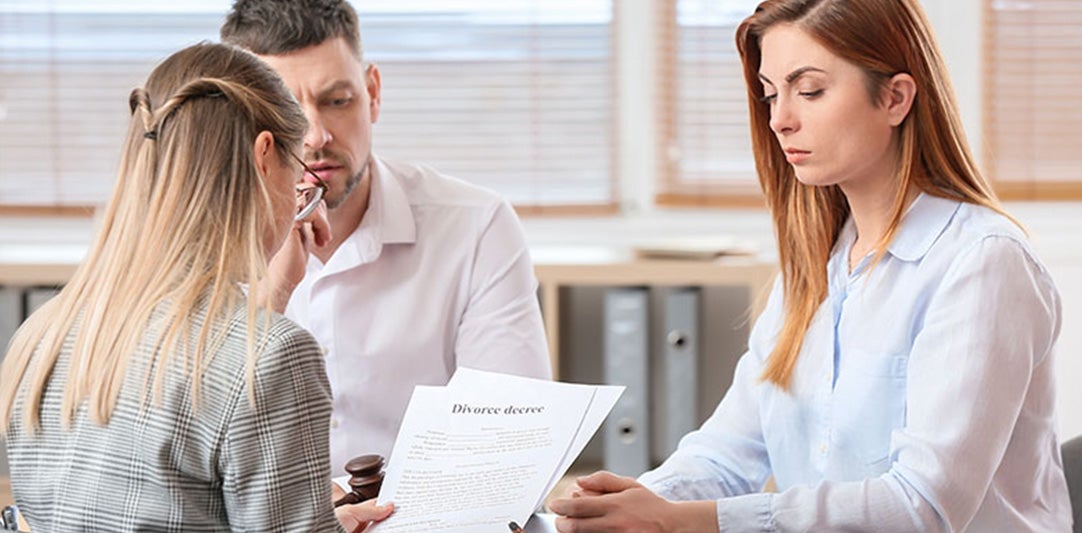 A couple reviews a 'Divorce decree' document with a female legal professional.